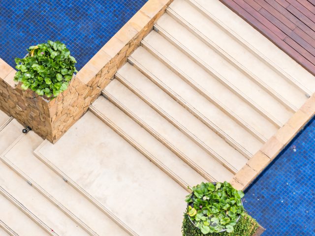 image about how to choose the right marble for outdoor space. Aerial view of a swimming pool with beige marble cladding