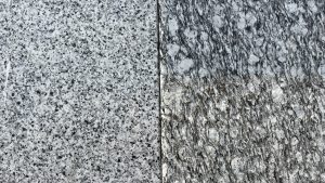 Close-up shot of granite rocks on the theme of "marble or granite." Two dark-colored, grainy granite rocks with a gray hue.